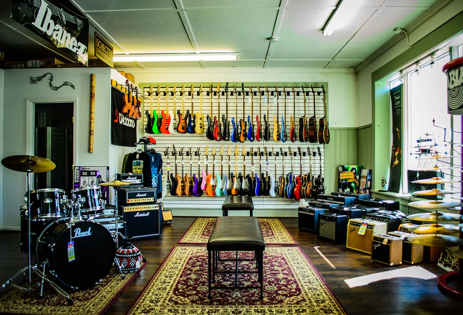 A room filled with lots of guitars and stands.