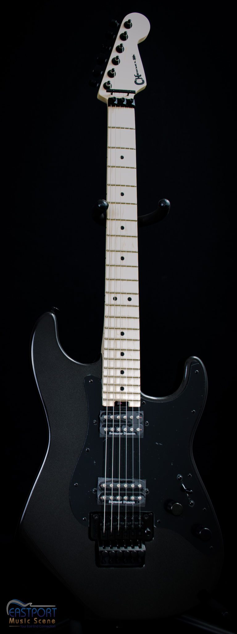 A black electric guitar with white strings and a black body.