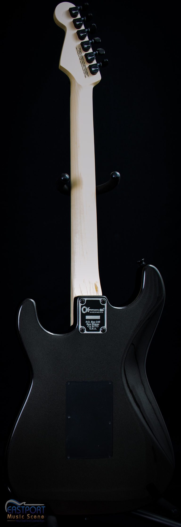A black electric guitar with white strings and a white handle.