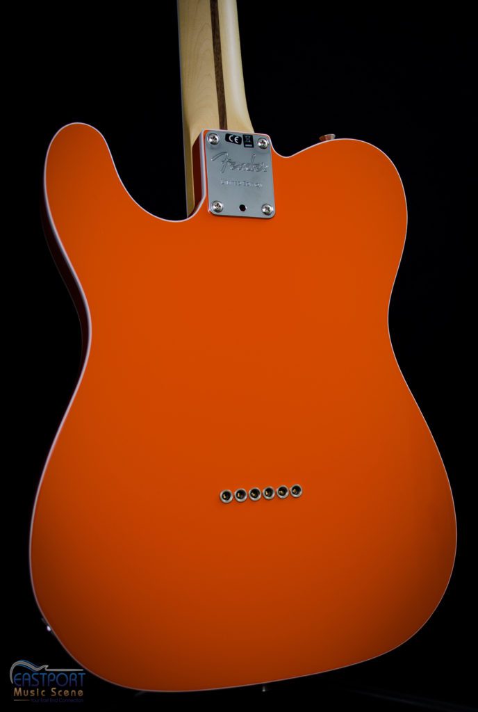 A close up of the back end of an orange guitar.