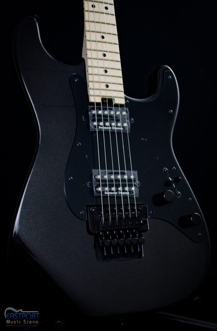 A black electric guitar with the strings missing.