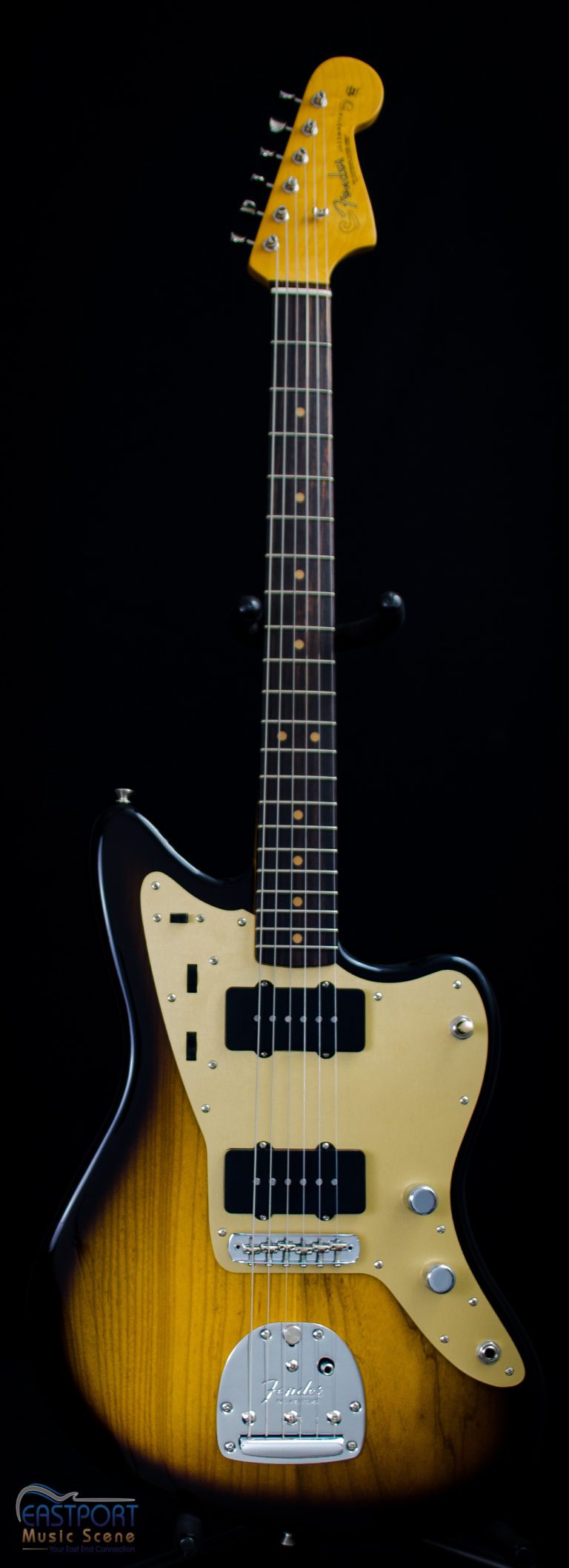 A black and white guitar is sitting in front of a black background.