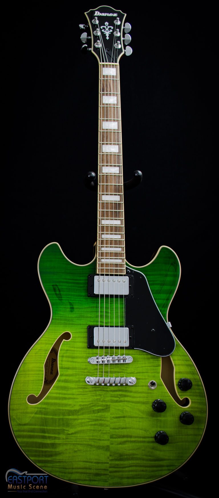 A green electric guitar with black trim and a white neck.