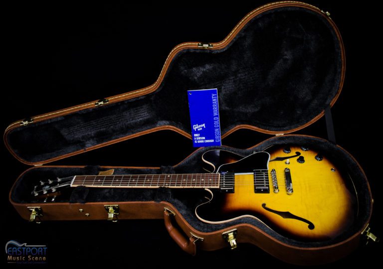 A guitar sitting in an open case next to another guitar.