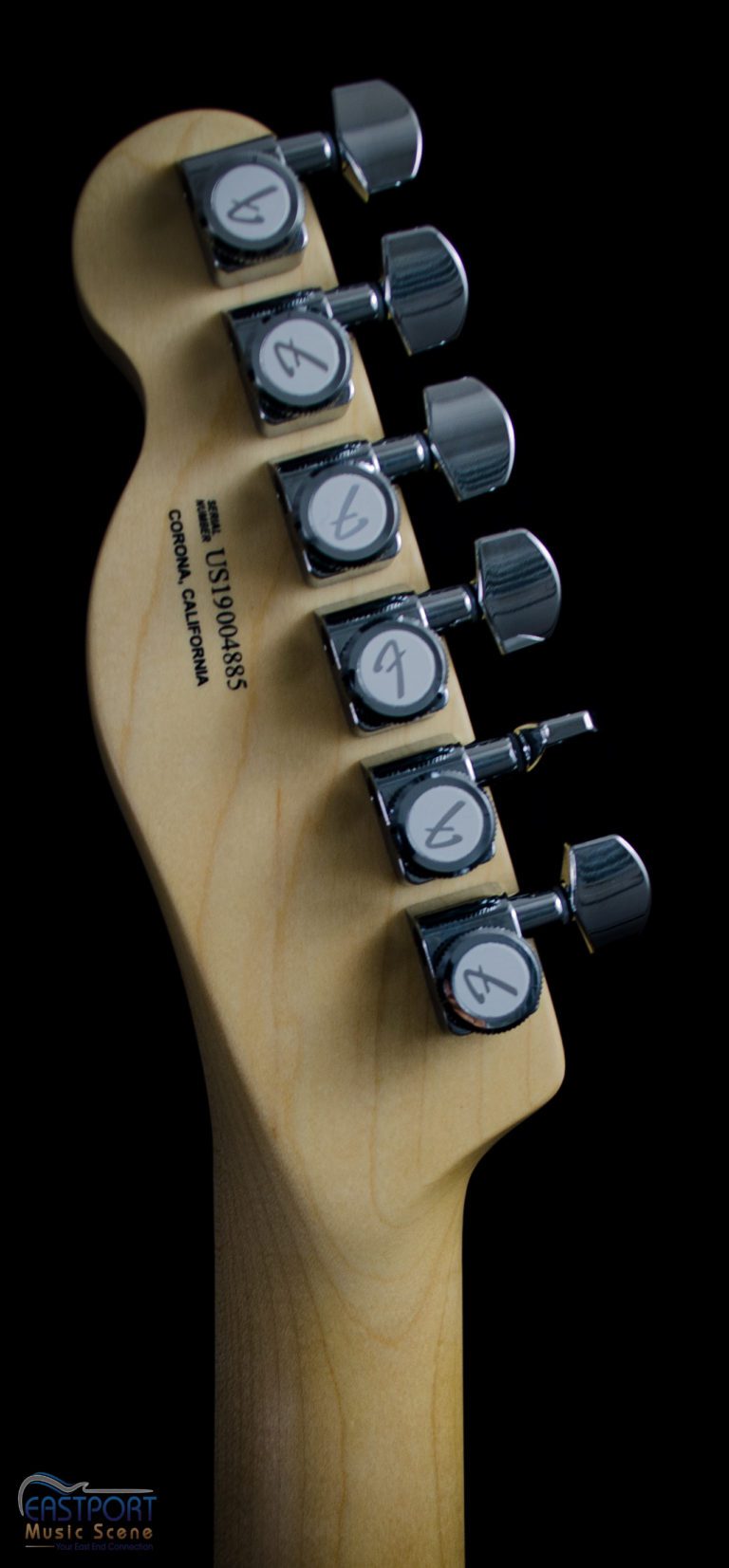 A guitar with four different tuning knobs.