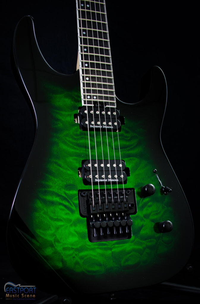 A green electric guitar with black trim and six strings.
