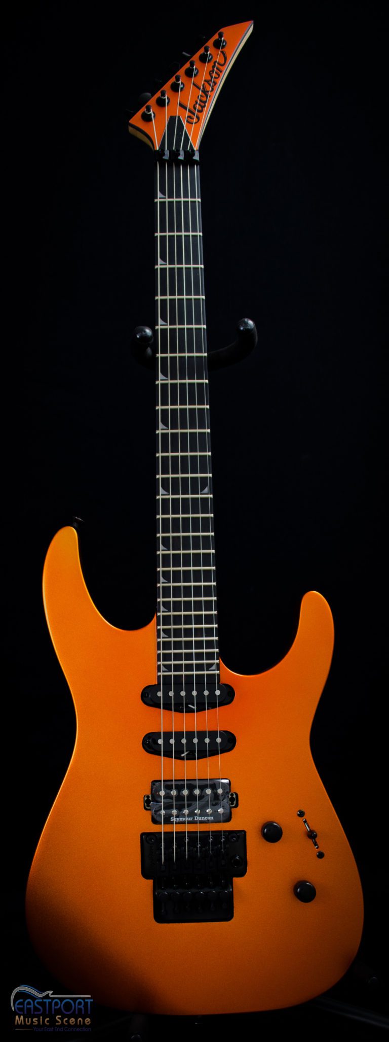 A close up of an orange electric guitar