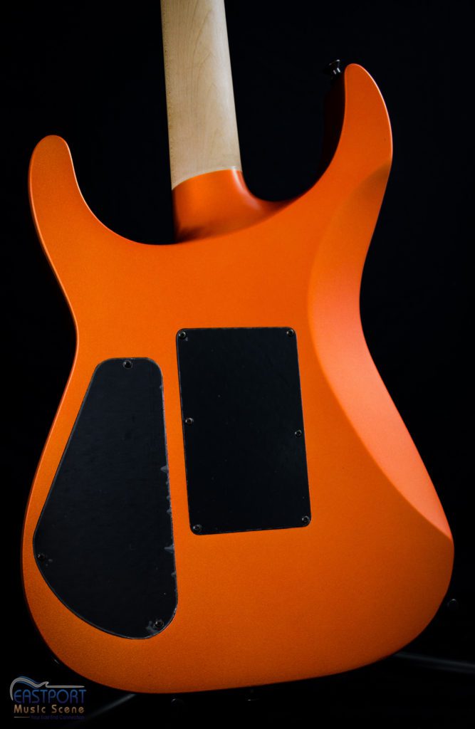 A close up of the neck and body of an orange electric guitar.