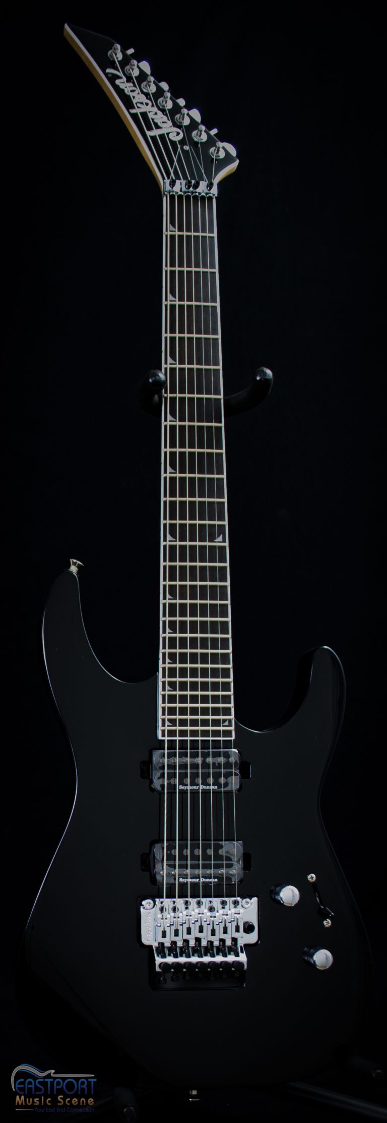 A black guitar is shown against a black background.
