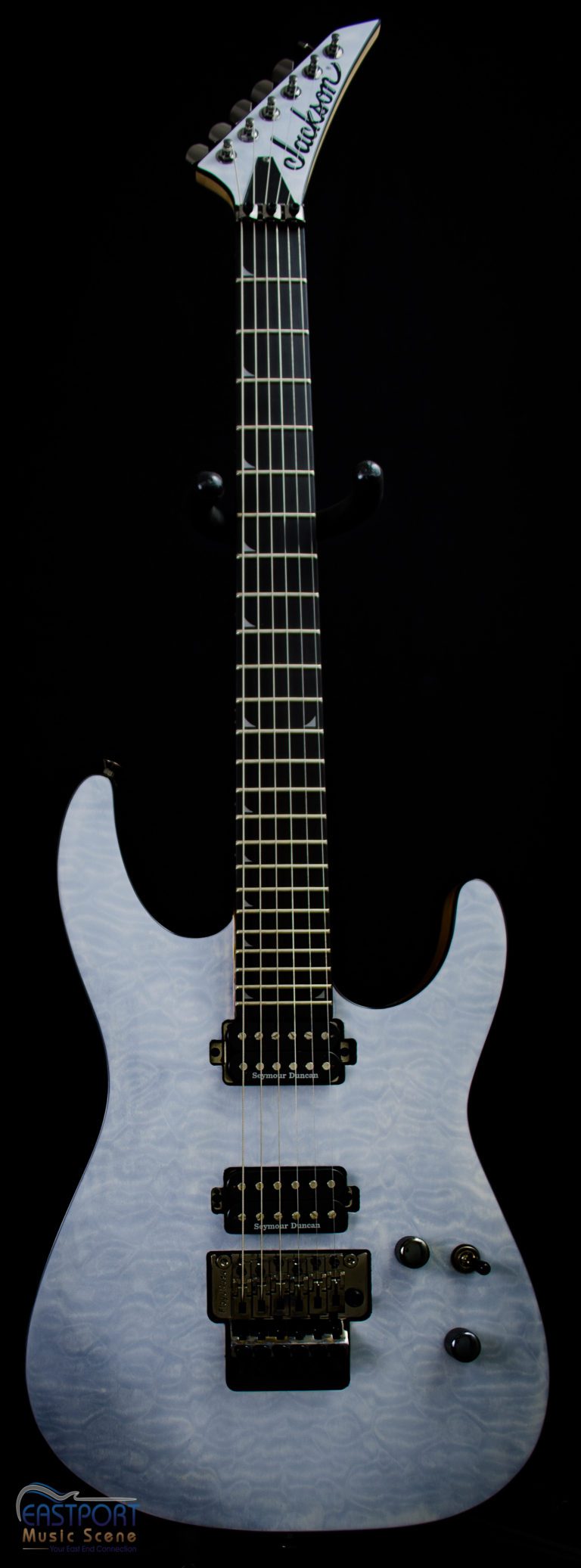 A white electric guitar with black strings and a black pick guard.