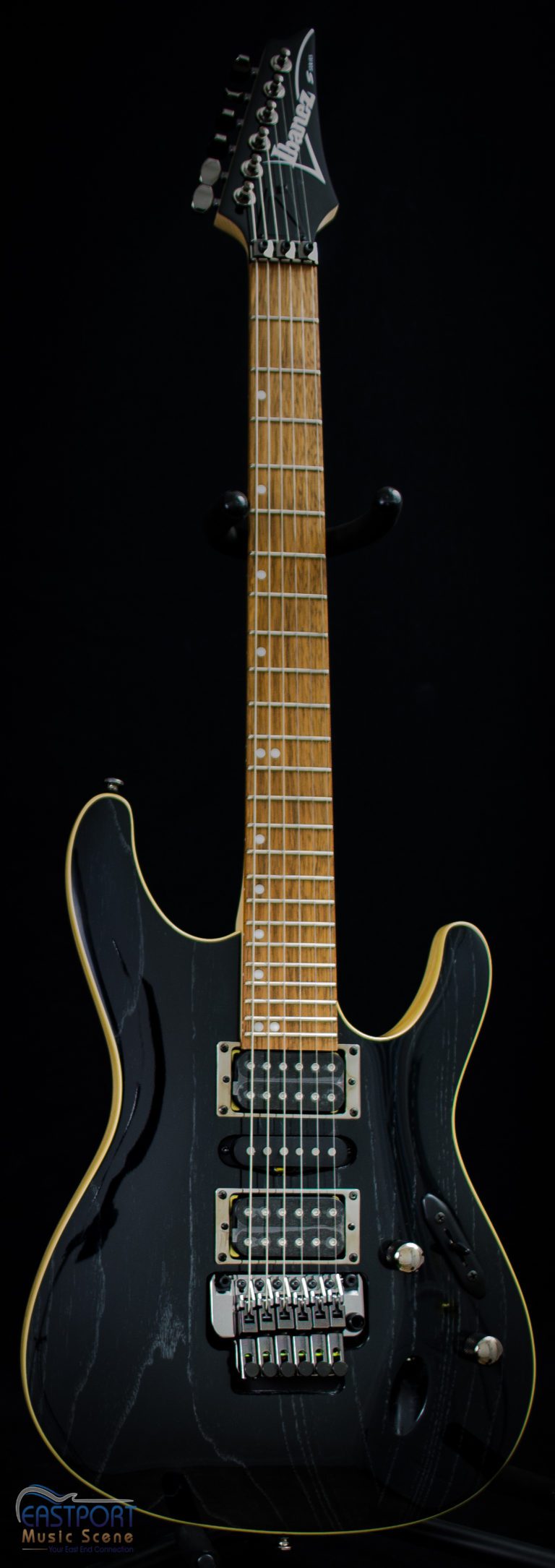 A black electric guitar with a yellow stripe on the neck.