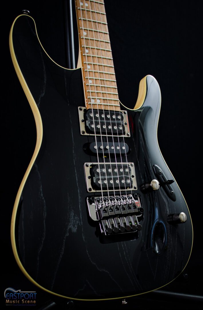 A black electric guitar with many strings and controls.