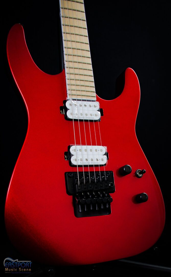 A red electric guitar with black strings and white headstock.