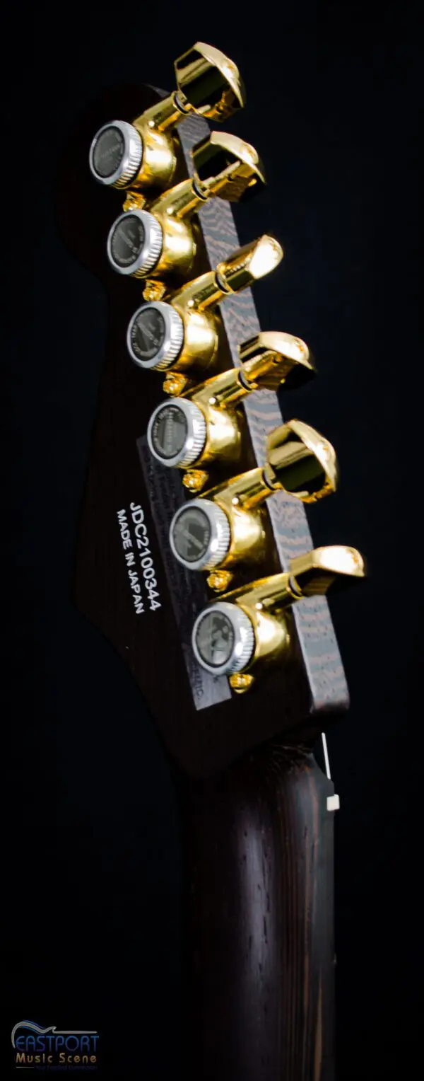 A guitar with four gold knobs on it.