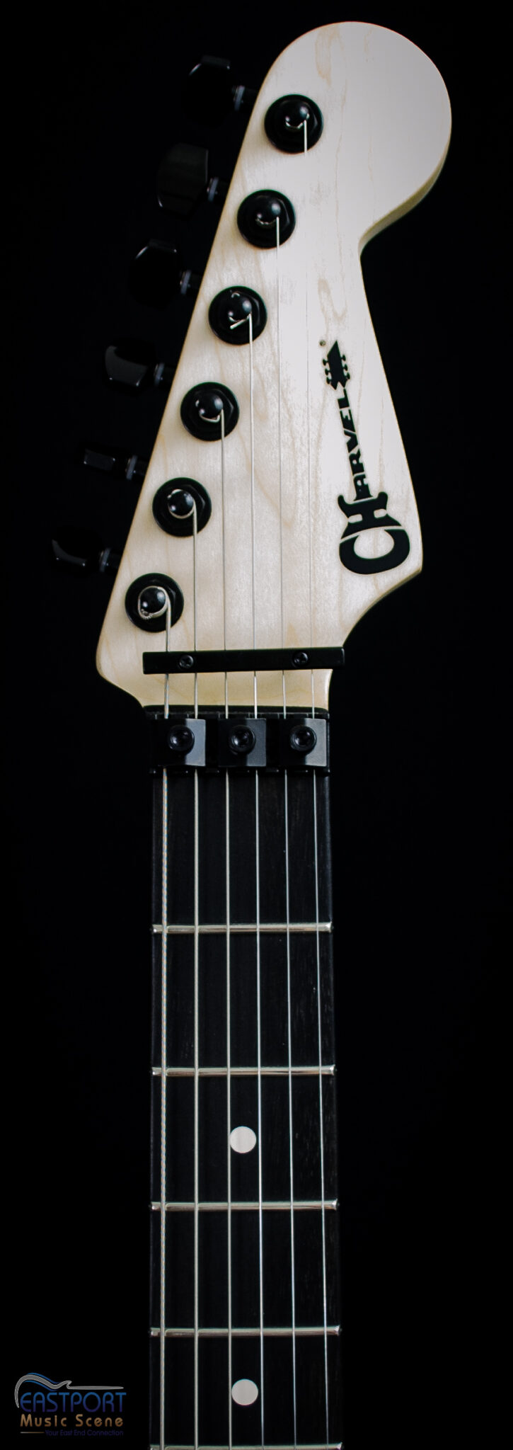 A close up of the neck and strings on an electric guitar.
