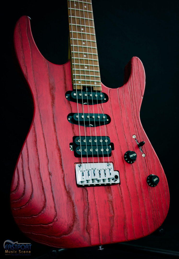 A red electric guitar with black strings and the top of it.
