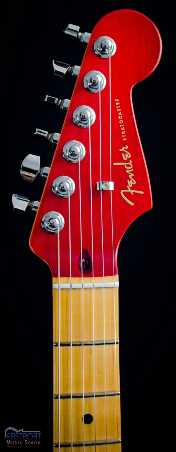 A red guitar with six strings and a yellow headstock.