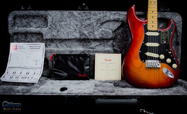 A guitar sitting on top of a bench next to some papers.