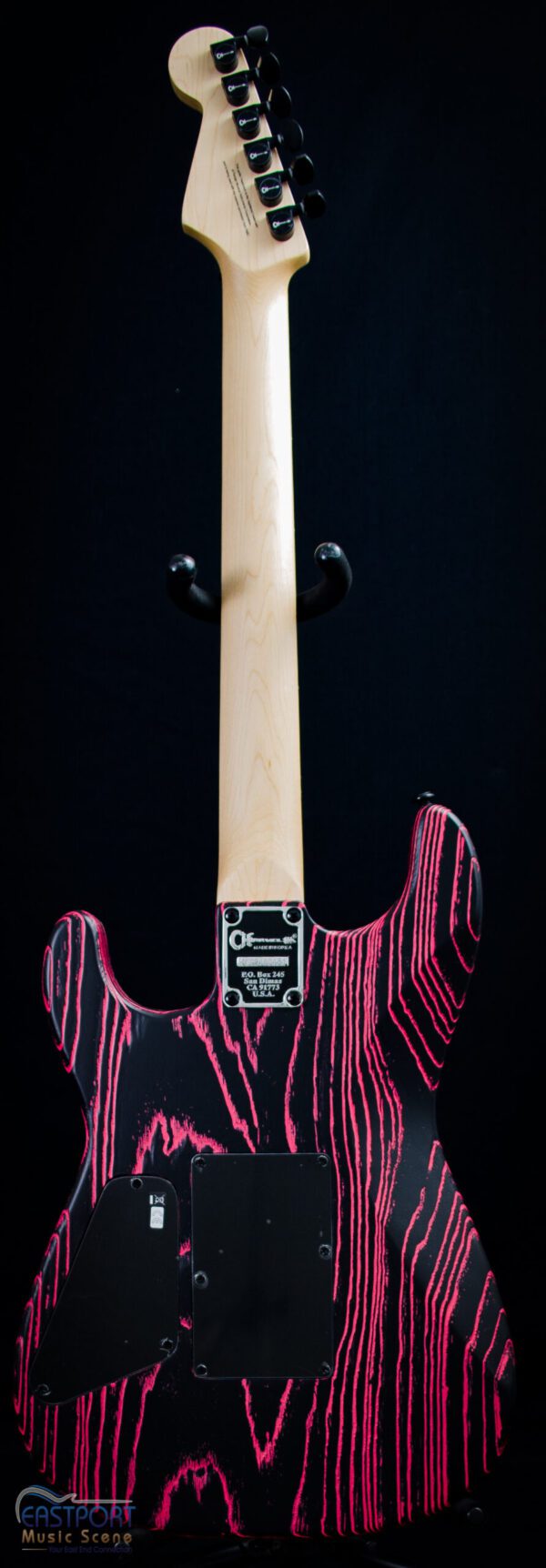 A pink and black electric guitar hanging on the wall